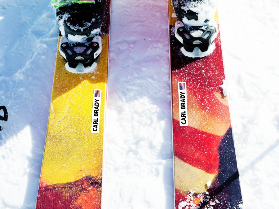 Witte naamstickers met vlag op de bovenkant van twee ski's